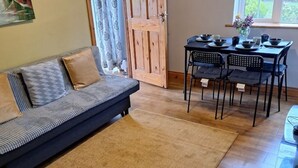 A living room with a sofa, a dining table with chairs, and a wooden door. - Welcome to Tunmobi Villa, home away from home.

 (Ballyjamesduff)