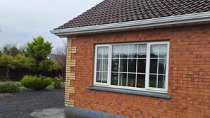 A brick house with a tiled roof, a large window, and a gravel driveway. - Welcome to Tunmobi Villa, home away from home.

 (Ballyjamesduff)