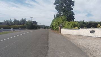 Une route tranquille, bordée d’une bande de gravier, d’un mur de pierres et d’un panneau indiquant « Sunnyside Villas ».