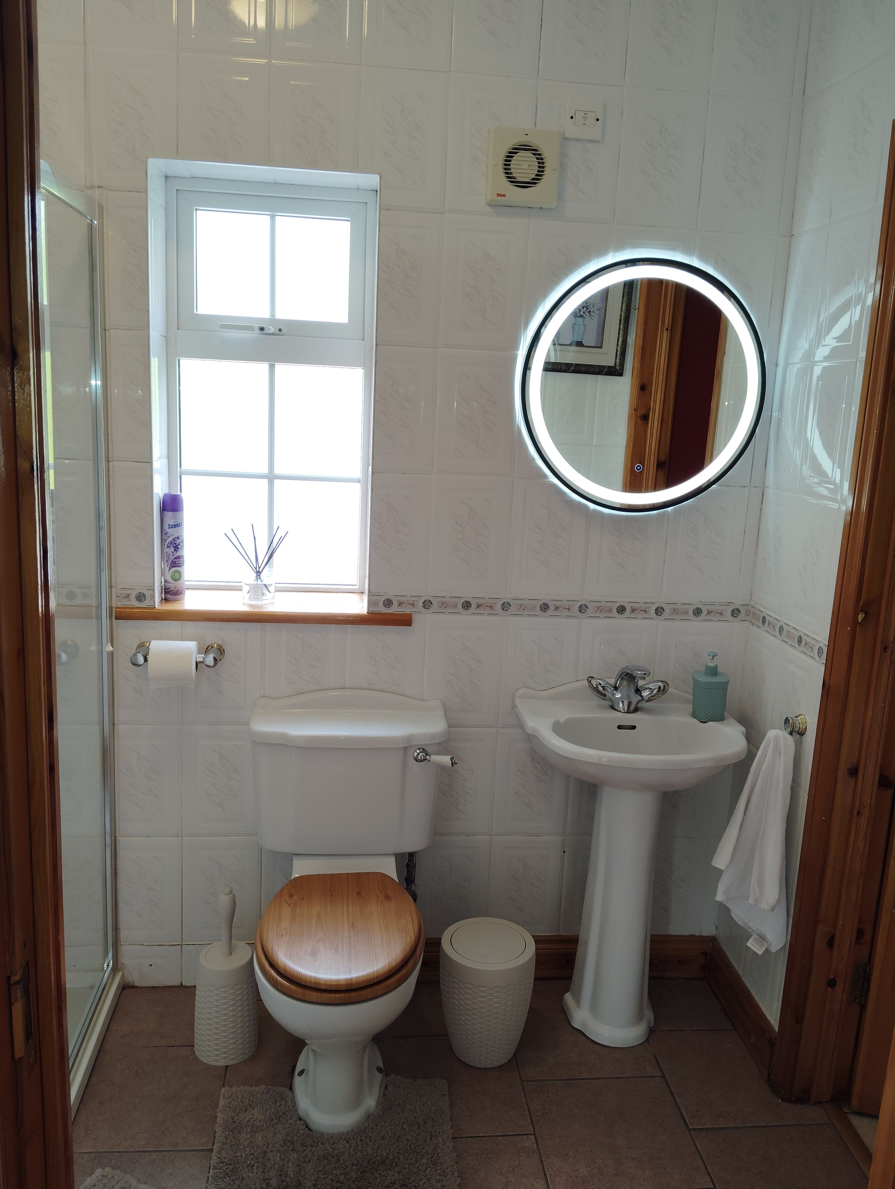 A bathroom with a toilet, sink, and window.