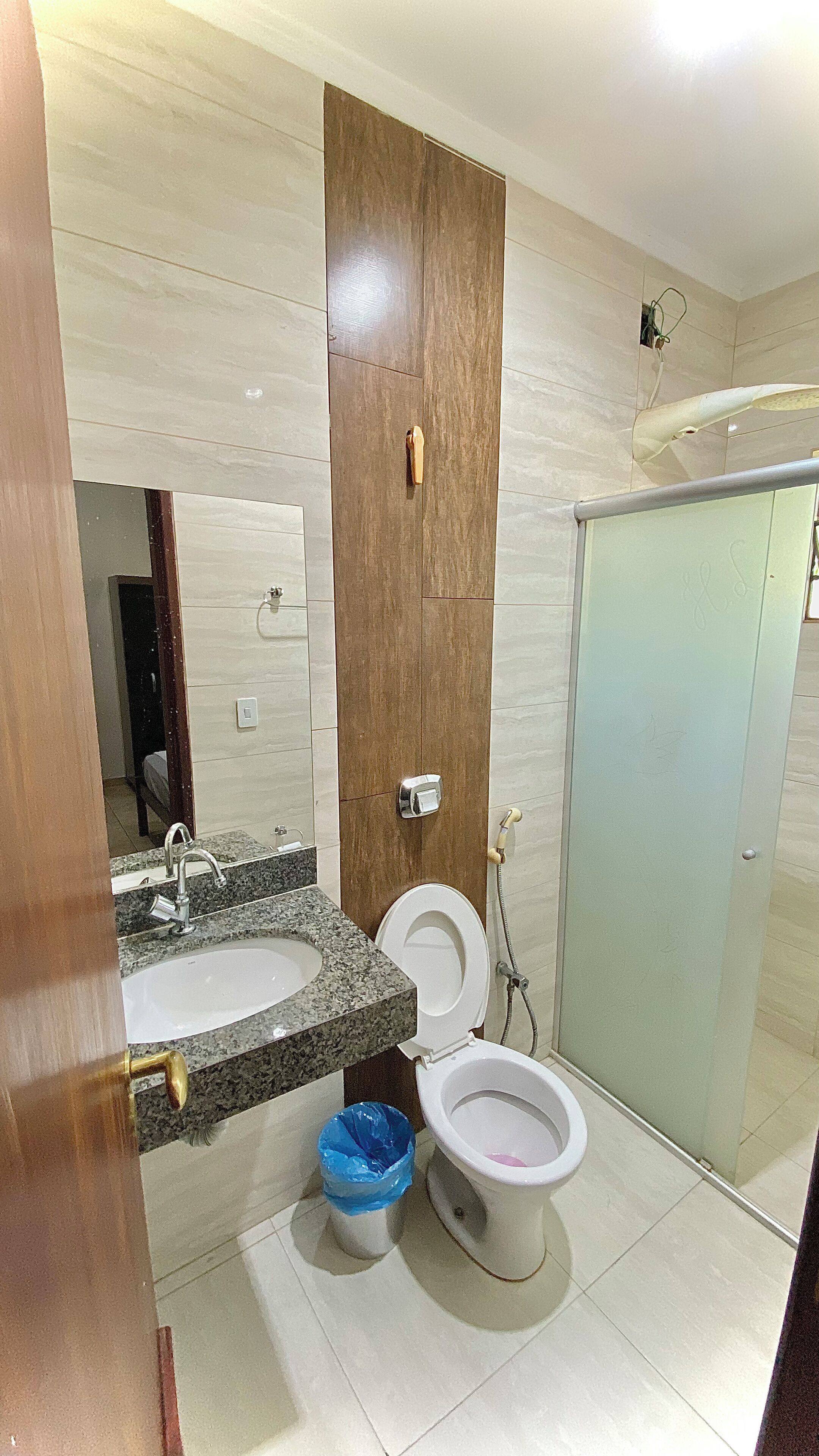 A bathroom with a wooden vanity, a sink, a toilet, and a shower area.