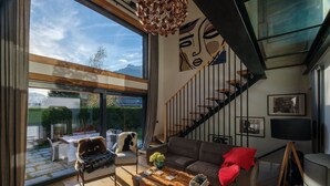 Una sala de estar moderna con un ventanal grande, una escalera y un sofá.
