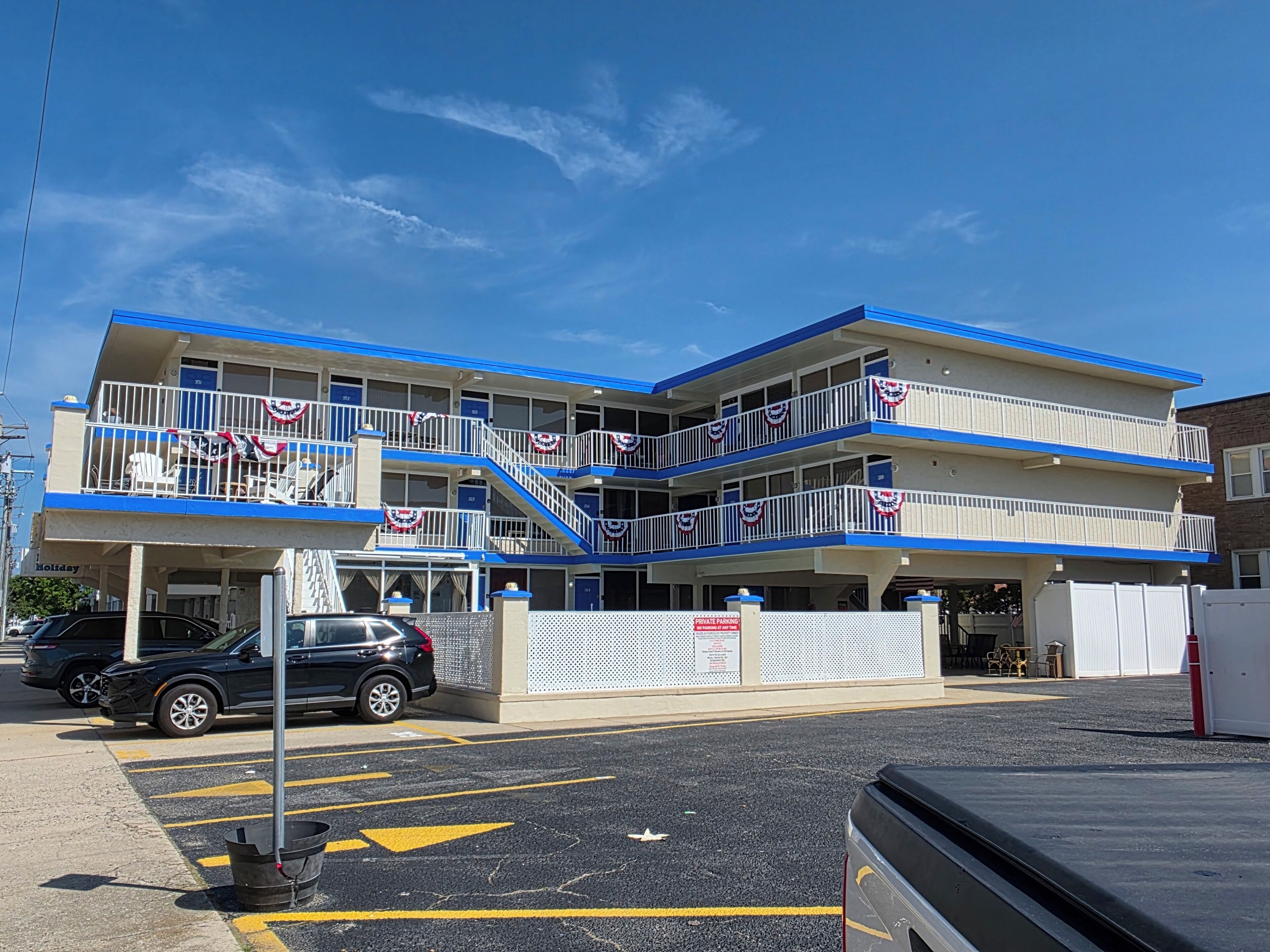 A multi-story motel with balconies, a parking area, and a sign indicating private parking.