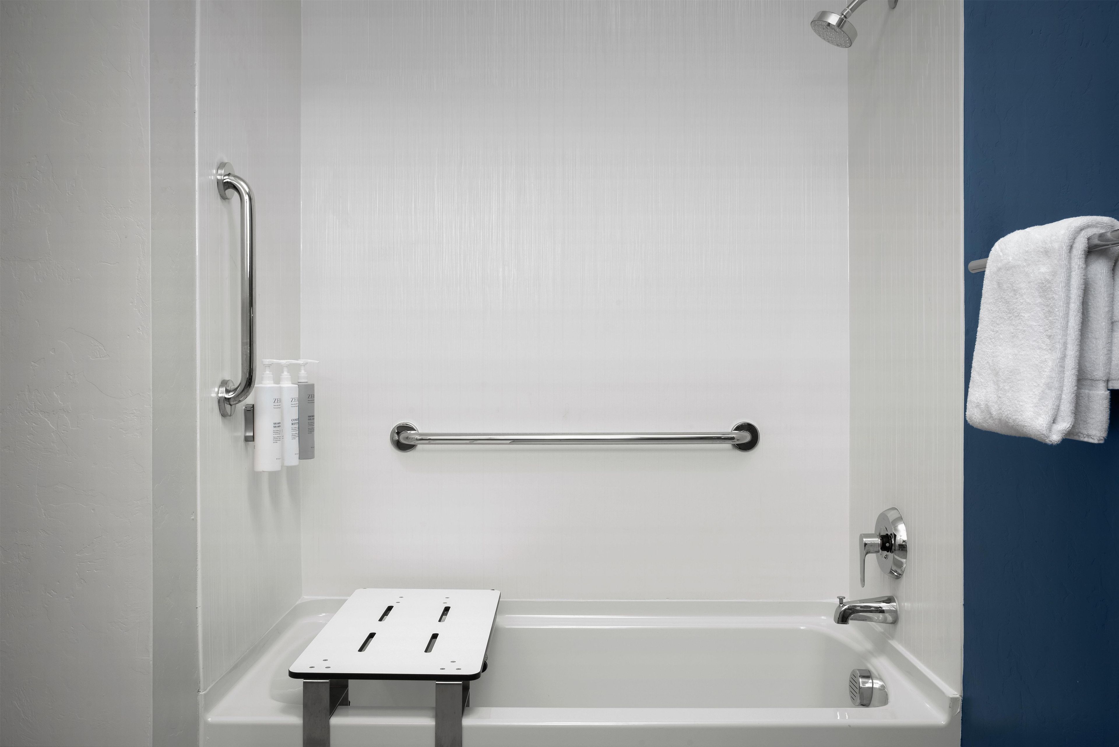 Un baño con bañera, barra de apoyo y perchero.