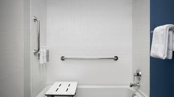 Un baño con bañera, barra de apoyo y perchero.