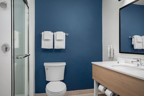 Un baño con pared azul, inodoro blanco y un lavabo con espejo encima.