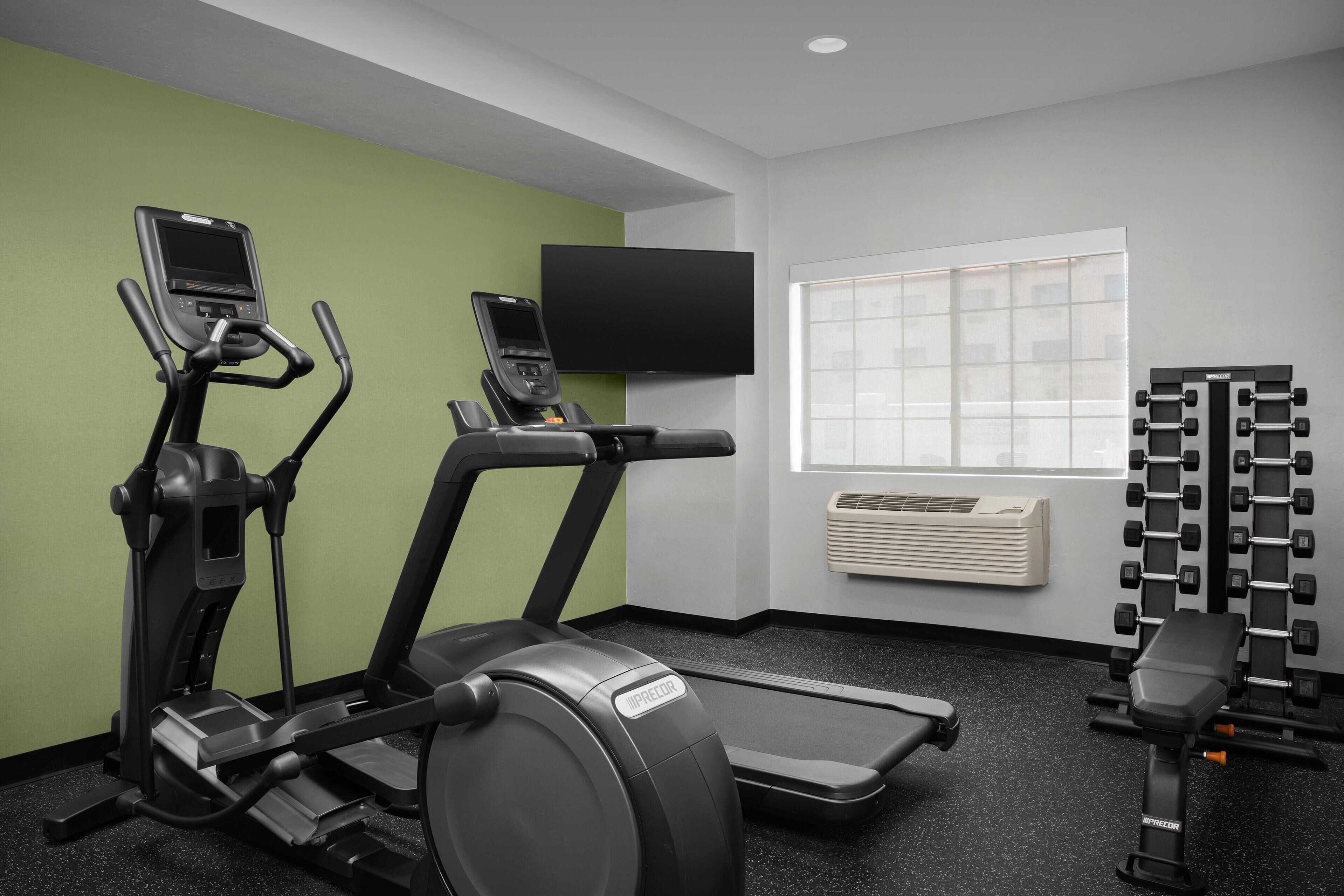 Ett gym med löpband, en crosstrainer och en viktbänk.