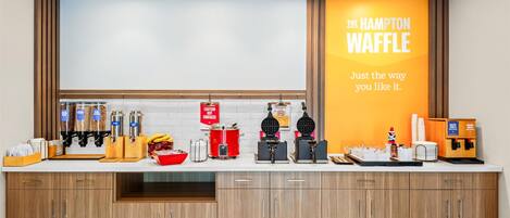 Un espace cuisine équipé d’une machine à gaufres, d’une machine à café et d’une pancarte indiquant : « The Hampton Waffle ».