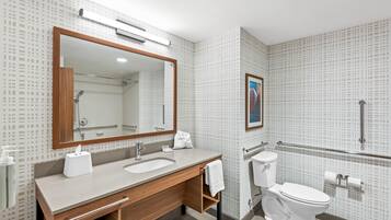 A modern bathroom with a wooden vanity, a large mirror, a toilet, and a shower area.