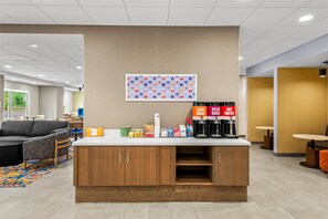 A modern kitchenette with a coffee machine, water dispenser, and snack options.