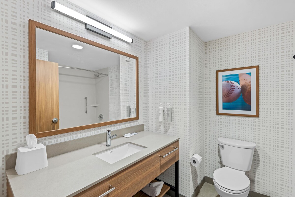 A modern bathroom with a large mirror, a sink, and a toilet.