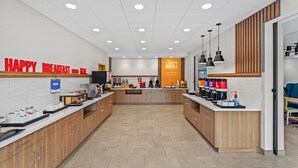 A modern breakfast area with a counter, coffee machines, and a sign that reads "HAPPY BREAKFAST." - Hampton Inn Cooperstown (Cooperstown)