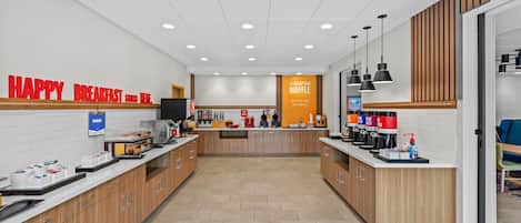 A modern breakfast area with a counter, coffee machines, and a sign that reads "HAPPY BREAKFAST."