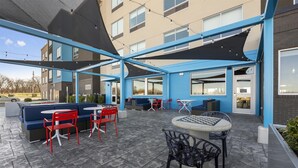 An outdoor patio area with seating arrangements, including a sofa and chairs, and a table. - Tru By Hilton Cape Girardeau (Cape Girardeau)