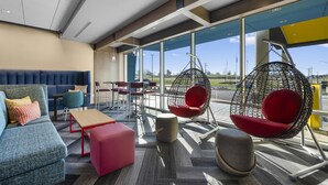 A modern lounge area with seating options including sofas, chairs, and a hanging chair, with large windows providing a view of the outdoors. - Tru By Hilton Cape Girardeau (Cape Girardeau)