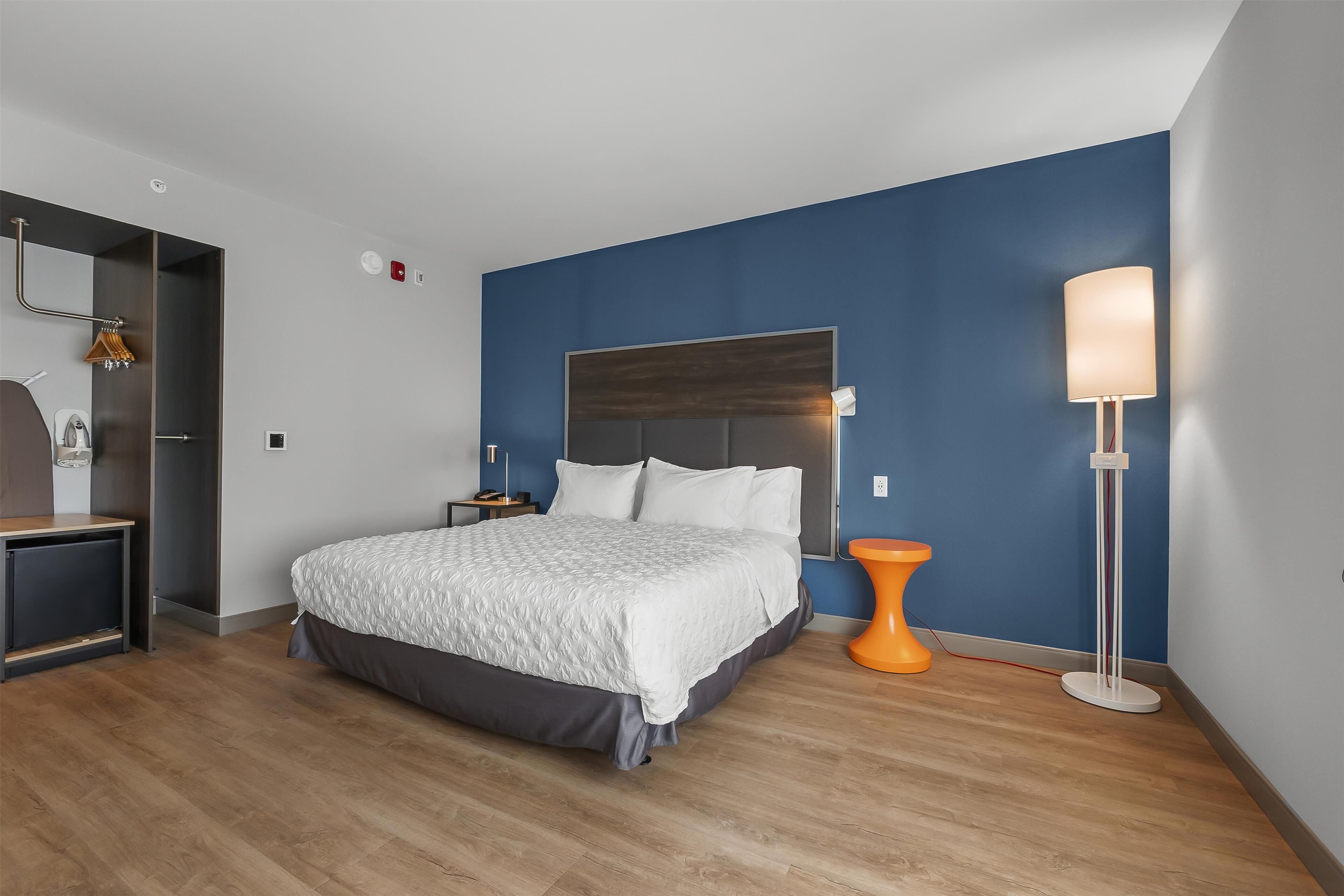 A modern bedroom with a bed, bedside table, and a floor lamp.
