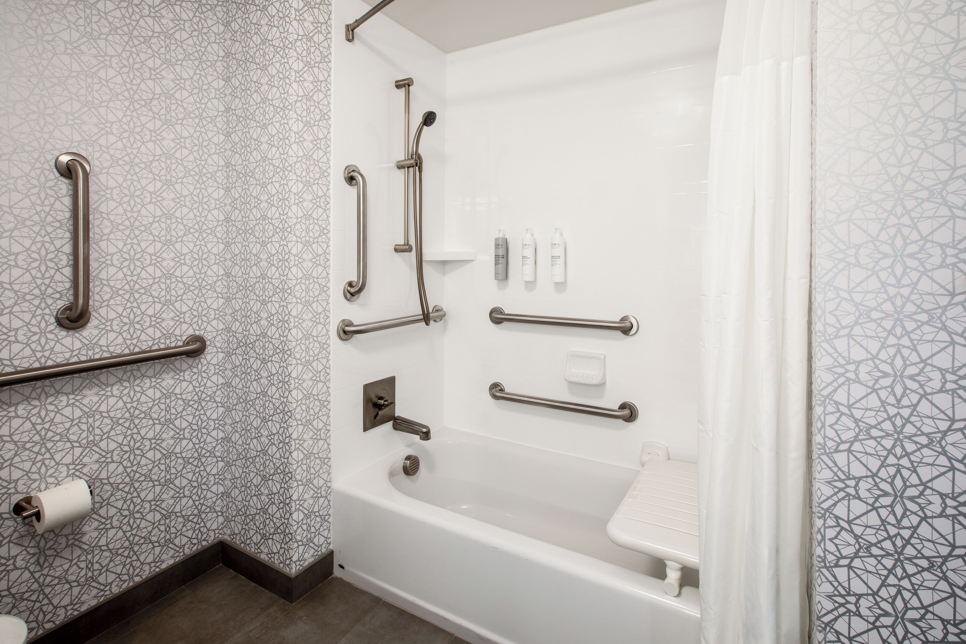 Une salle de bain équipée d’une baignoire, de barres d’appui et de toilettes.