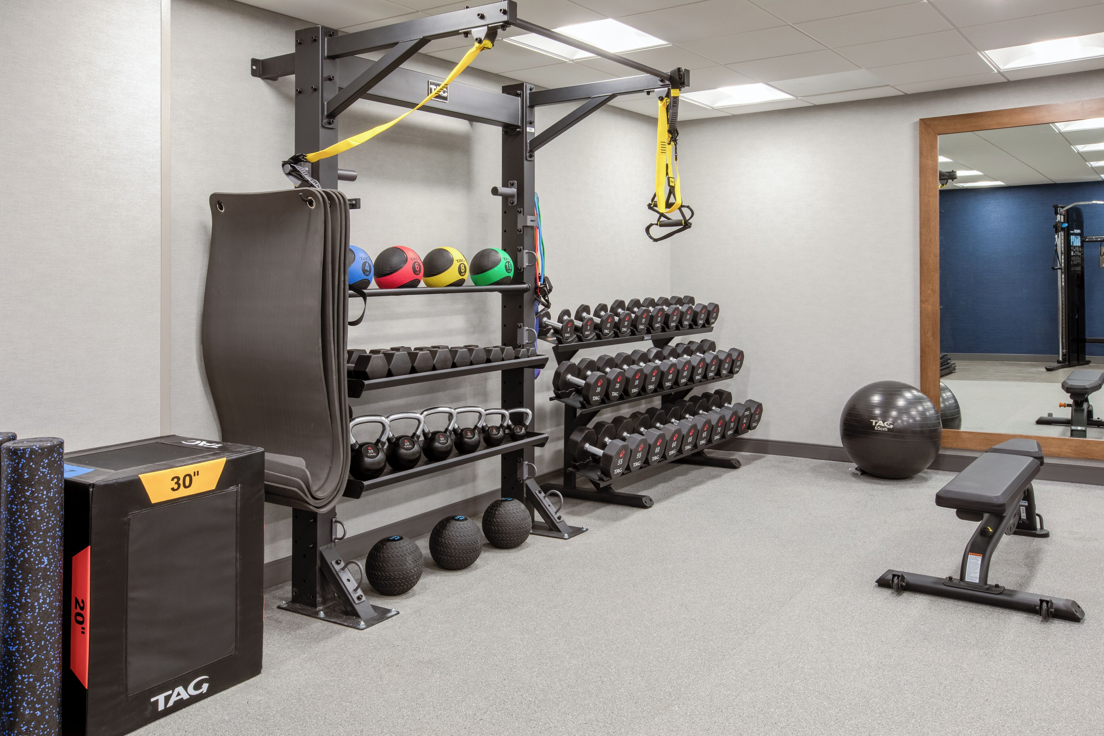 A gym with weightlifting equipment, exercise balls, and dumbbells.