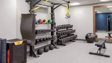 A gym with weightlifting equipment, exercise balls, and dumbbells.