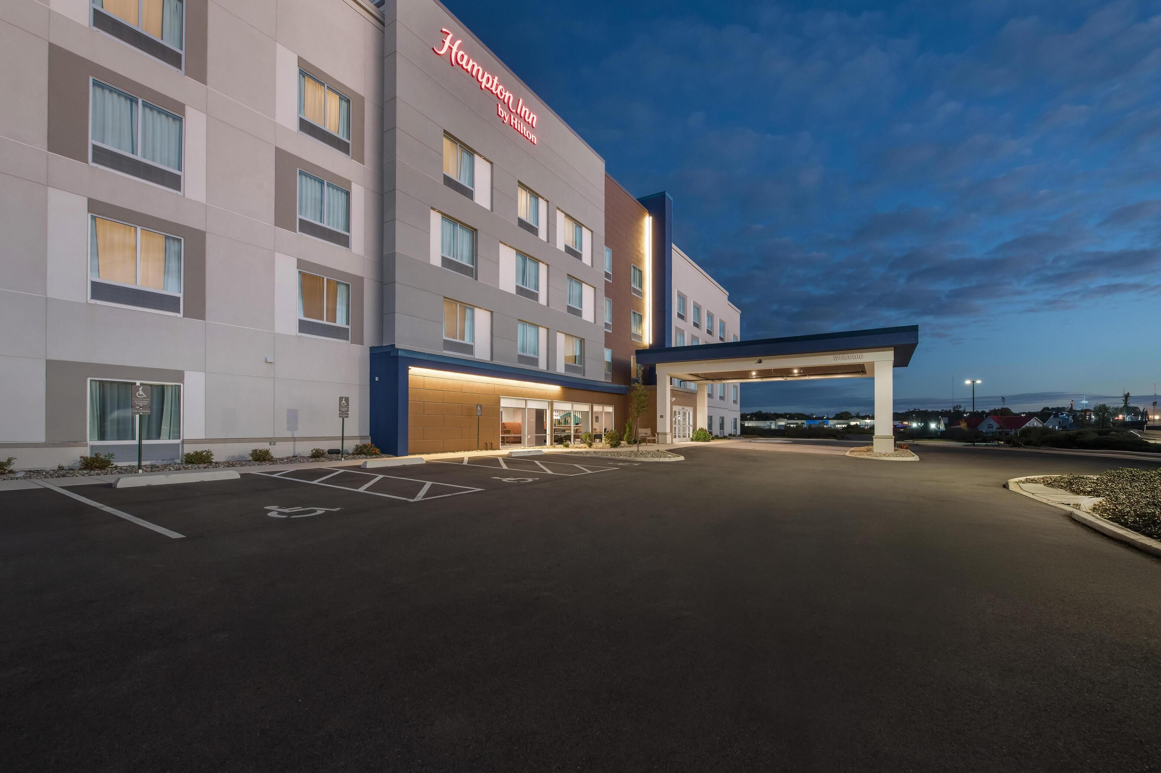 A Hampton Inn by Hilton hotel with a spacious parking lot and a covered entrance.