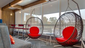 Ein modernes Interieur mit einem grauen Sofa, roten Sesseln und einem Hängesessel mit Metallgestell.