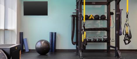 Une salle de sport équipée d’un support à squats, de kettlebells, de ballons d’exercice et d’élastiques de résistance.