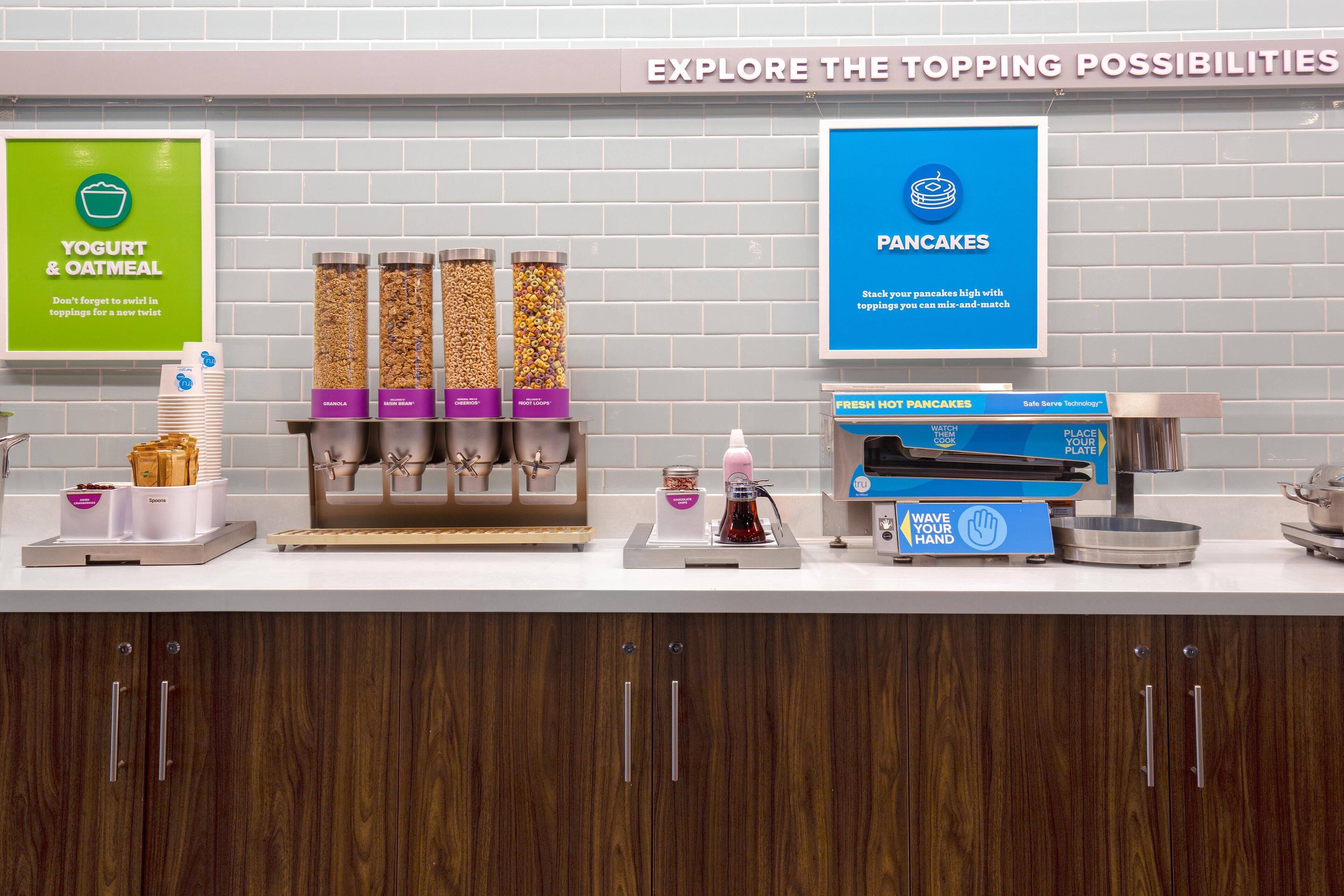 Un buffet pour le petit-déjeuner proposant des yaourts, du porridge et des crêpes, avec un choix de garnitures et un espace en libre-service.