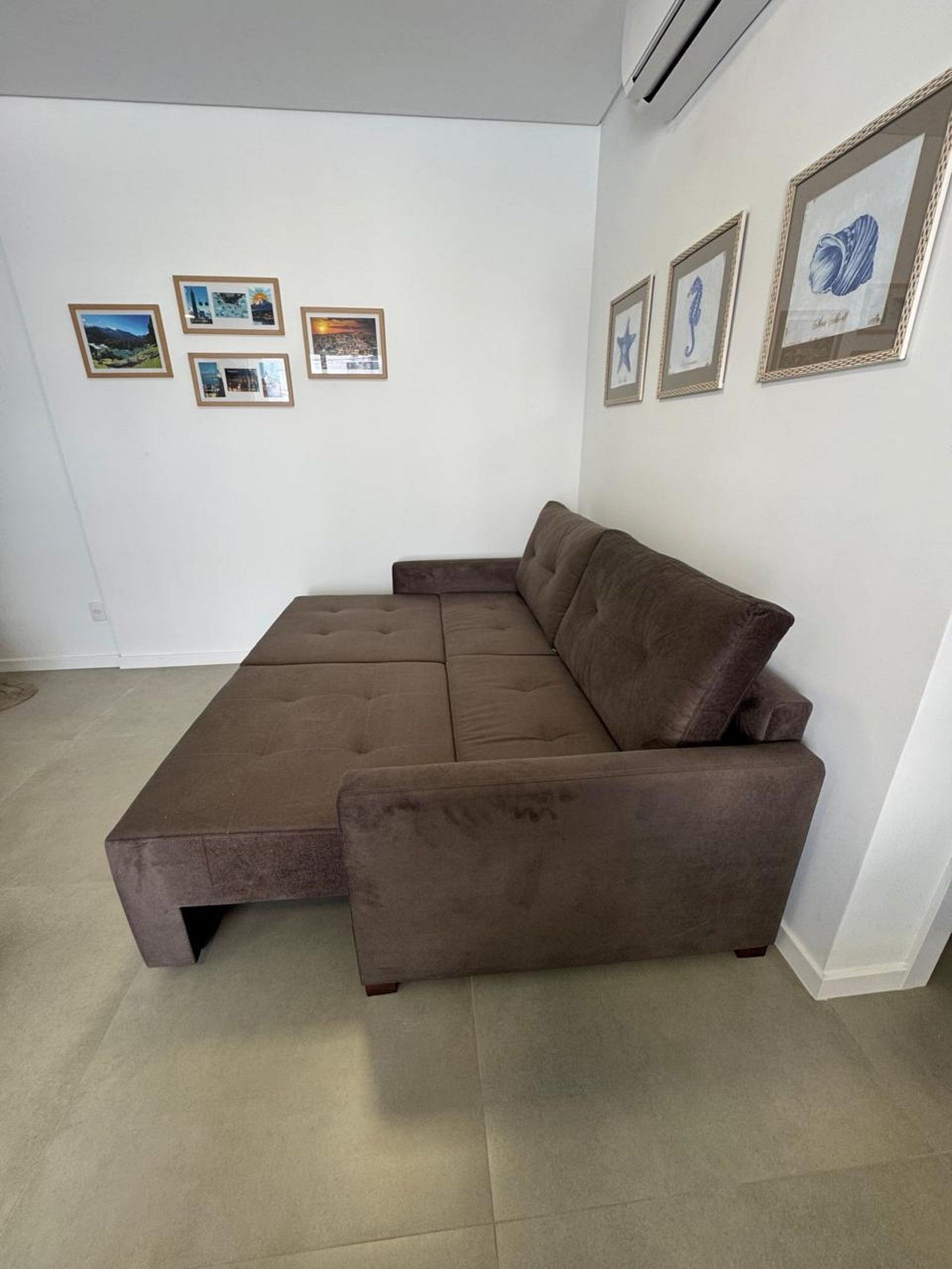 A modern living room with a brown sectional sofa, a flat-screen TV, and framed artwork on the walls.