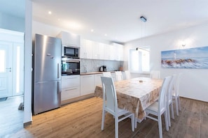 Enjoy meals at the dining table for four, surrounded by a large window and a beautiful coastal-themed painting.