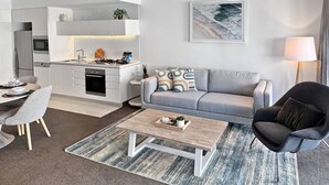 A modern living room with a grey sofa, a wooden coffee table, and a black armchair. - Perfect beach pad Oracle Tower 2 Lvl 8 Parking (Broadbeach)