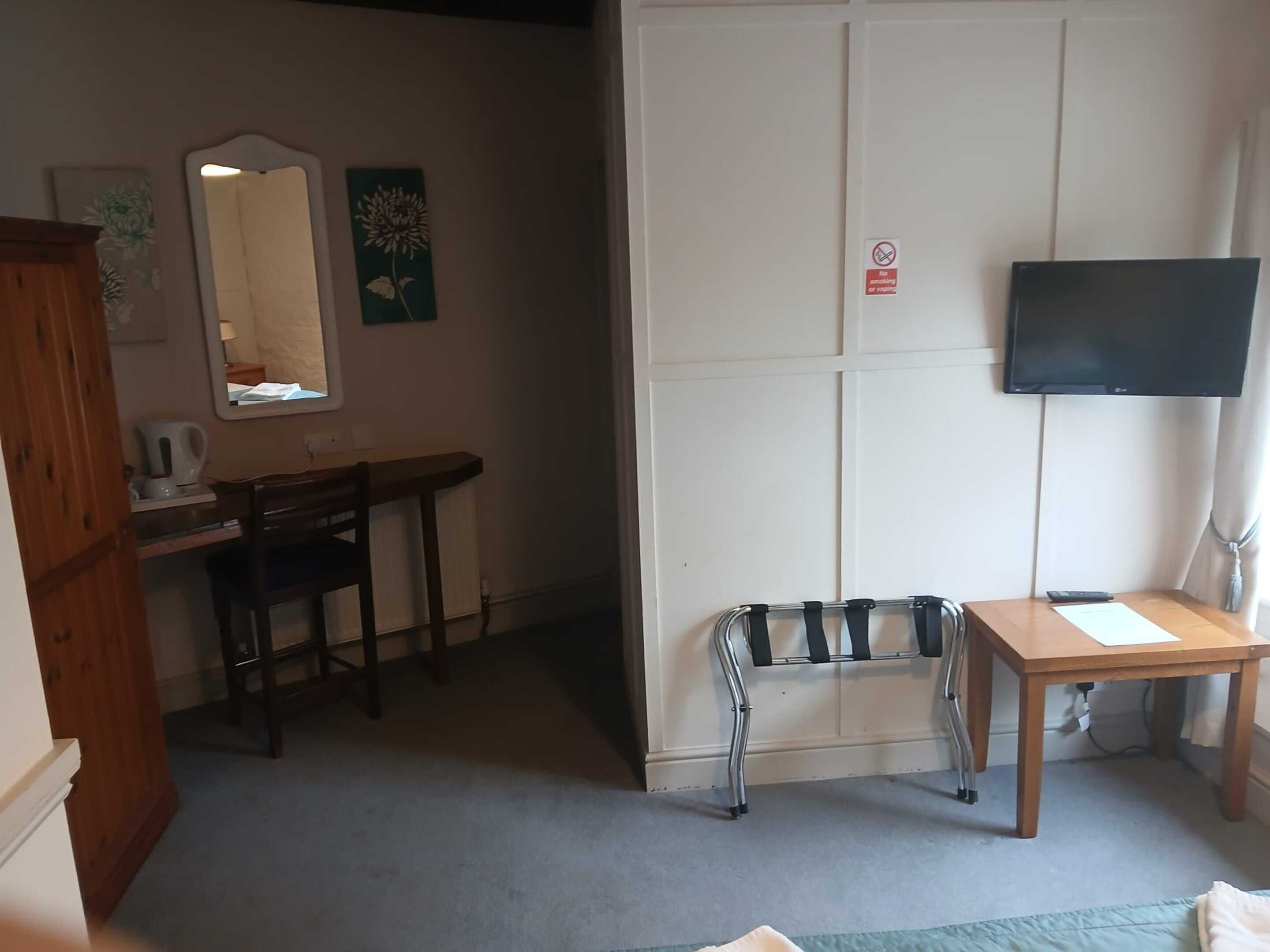 Una habitación con escritorio, silla, cama y televisor montado en la pared.