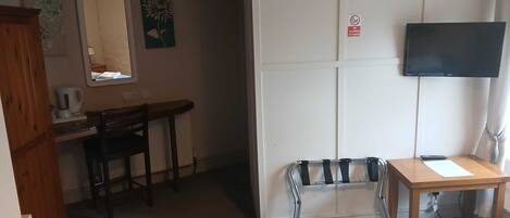 Una habitación con escritorio, silla, cama y televisor montado en la pared.