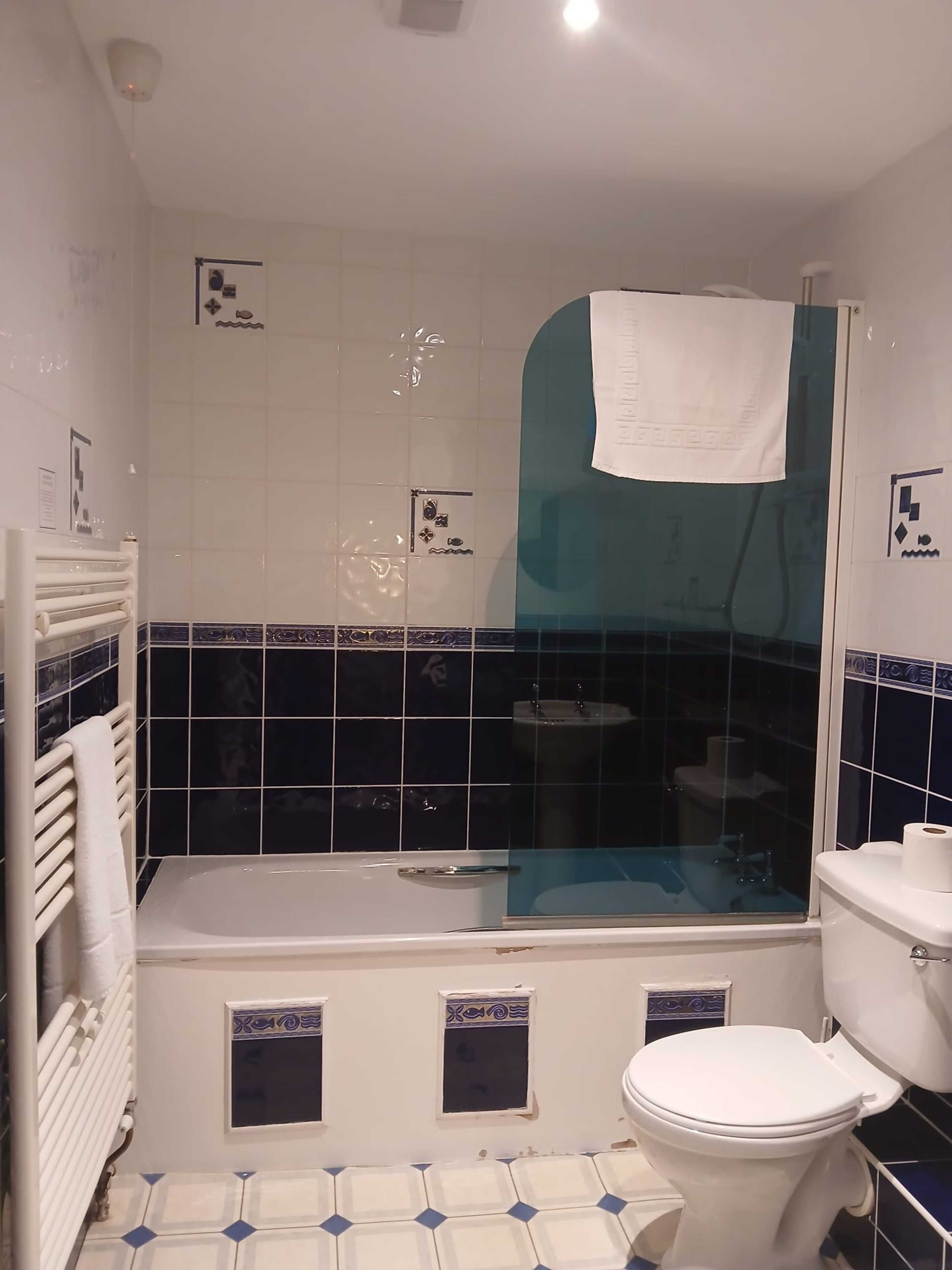 A bathroom with a bathtub, toilet, and shower enclosure.