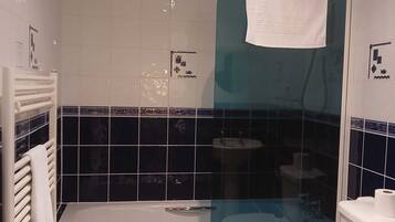 A bathroom with a bathtub, toilet, and shower enclosure.