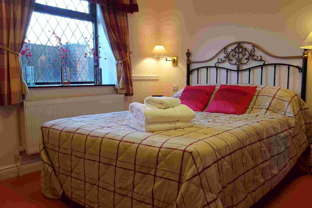 A neatly made bed with a quilted bedspread, two pillows, and a folded towel.