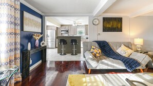 A modern living room with a sofa, coffee table, and a dining area with a bar. - Home Near Parks & Downtown Worcester (Worcester)