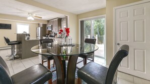 A modern kitchen with a glass dining table, black chairs, and a ceiling fan. - Home Near Parks & Downtown Worcester (Worcester)