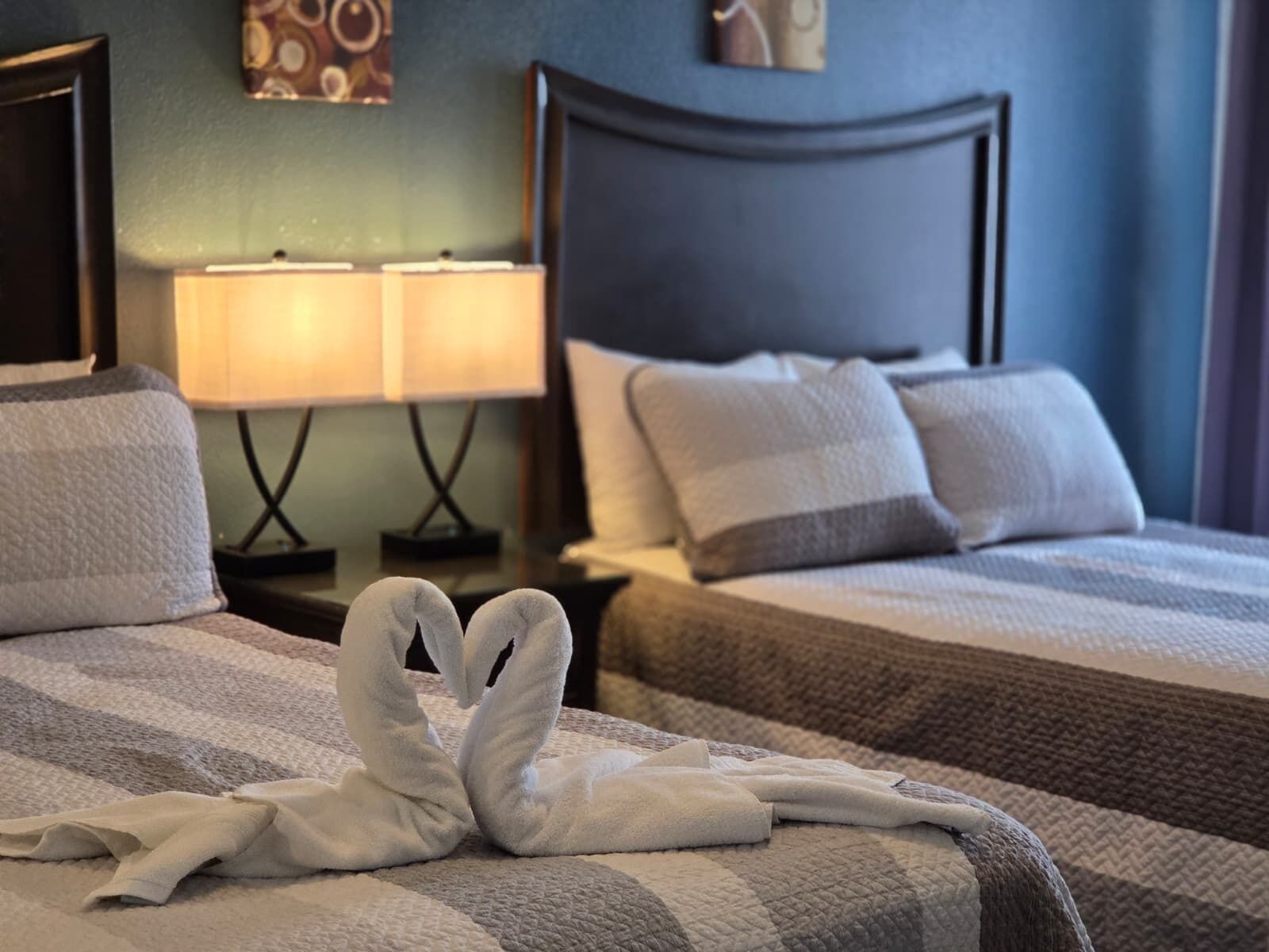 Une chambre d’hôtel avec deux lits, une table de chevet avec des lampes et un élément décoratif mural.