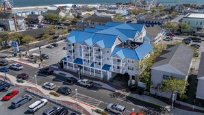 A multi-story hotel with a blue roof, located near a beach and a large Ferris wheel. - OCbeachparadise, Paradise Off The Boardwalk (Ocean City)