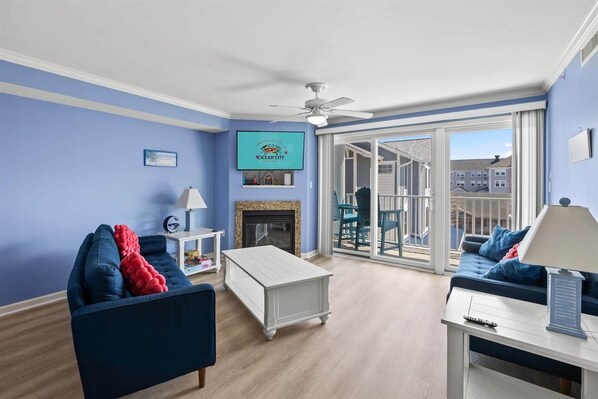 A living room with a fireplace, a ceiling fan, and a TV mounted on the wall.