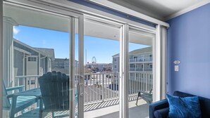 A balcony with a glass door, a chair, and a blue sofa. - OCbeachparadise, Paradise Off The Boardwalk (Ocean City)