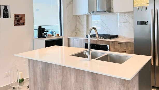 A modern kitchen with a large island, stainless steel appliances, and a marble backsplash. - Brand new apt w 2 Bedrooms Terrace in Cap Cana (Punta Cana)
