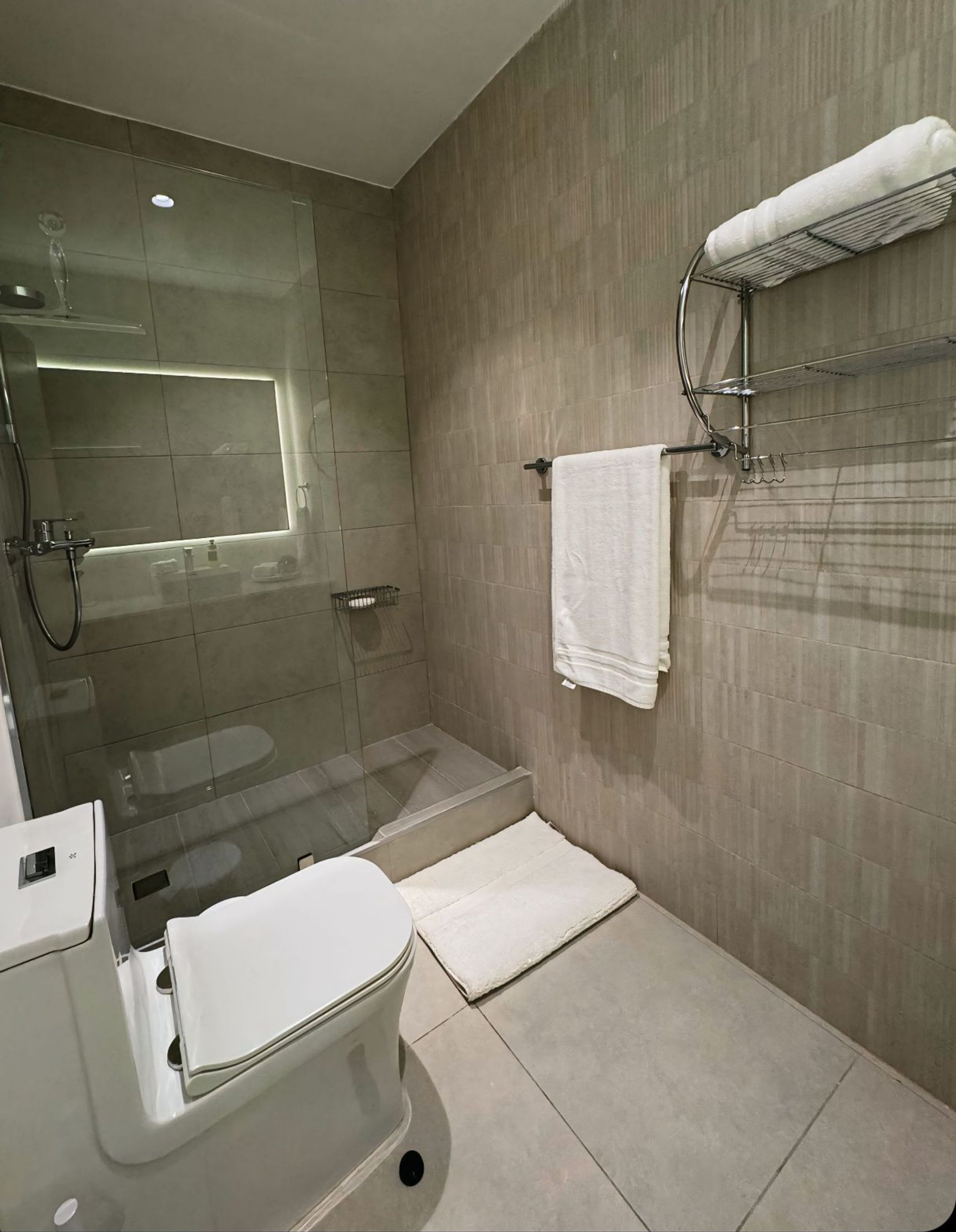 Ein modernes Badezimmer mit einer Duschkabine, einer Toilette und einem Handtuchhalter.