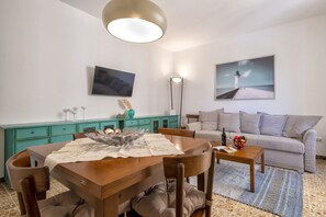 Una sala de estar con mesa de comedor, sofá y obras de arte en las paredes.