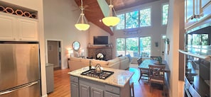 A modern kitchen with a central island, a dining area with a wooden table, and a cozy living space with a fireplace.