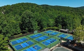 Un complejo de canchas de tenis rodeado de un bosque frondoso.