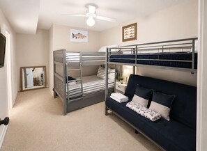 A bunk bed room with a desk and chair, a ceiling fan, and a framed fish picture on the wall.