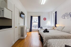 Hotelkamer met twee bedden, een televisie, een magnetron en een balkon met uitzicht op de stad.