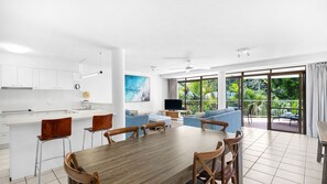 Ein modernes Interieur mit einer Küche, einem Essbereich und einem Balkon mit Blick auf Grünflächen.