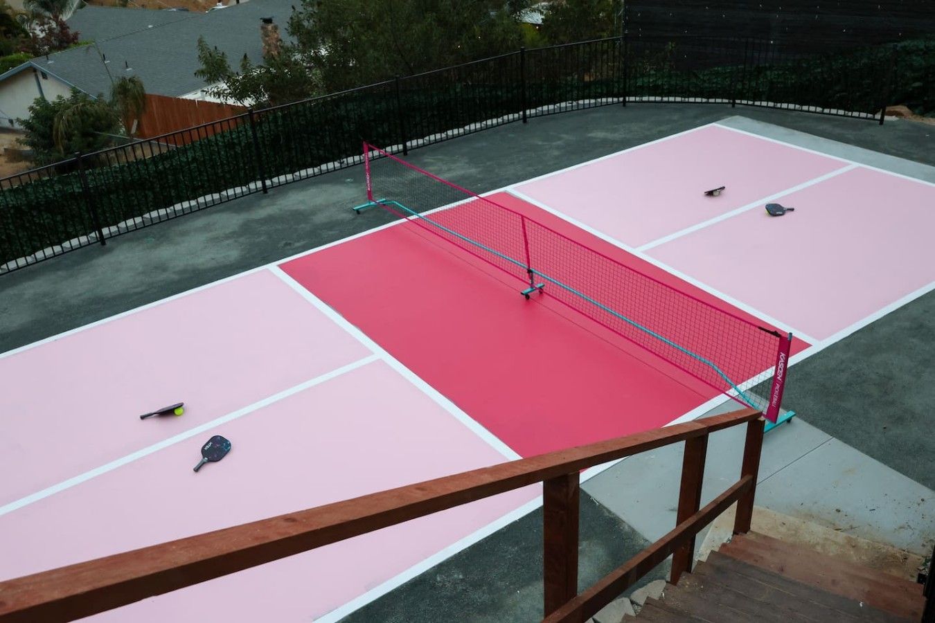 Una cancha de tenis al aire libre con una red, dos raquetas de tenis y un volante.